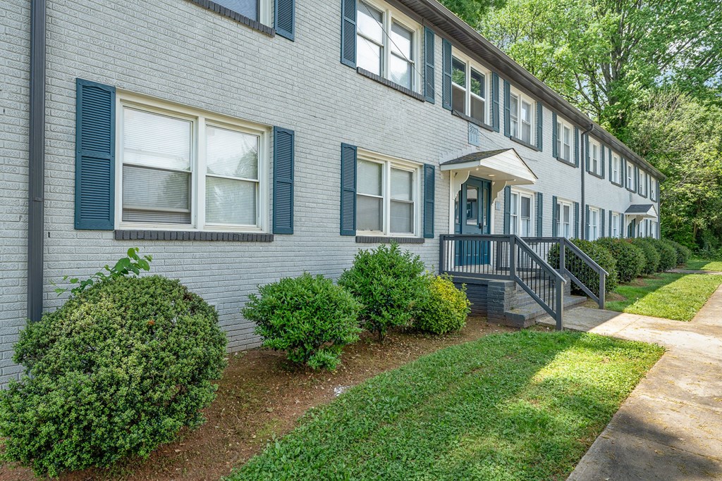 a white house with blue shuttered windows and a sidewalk