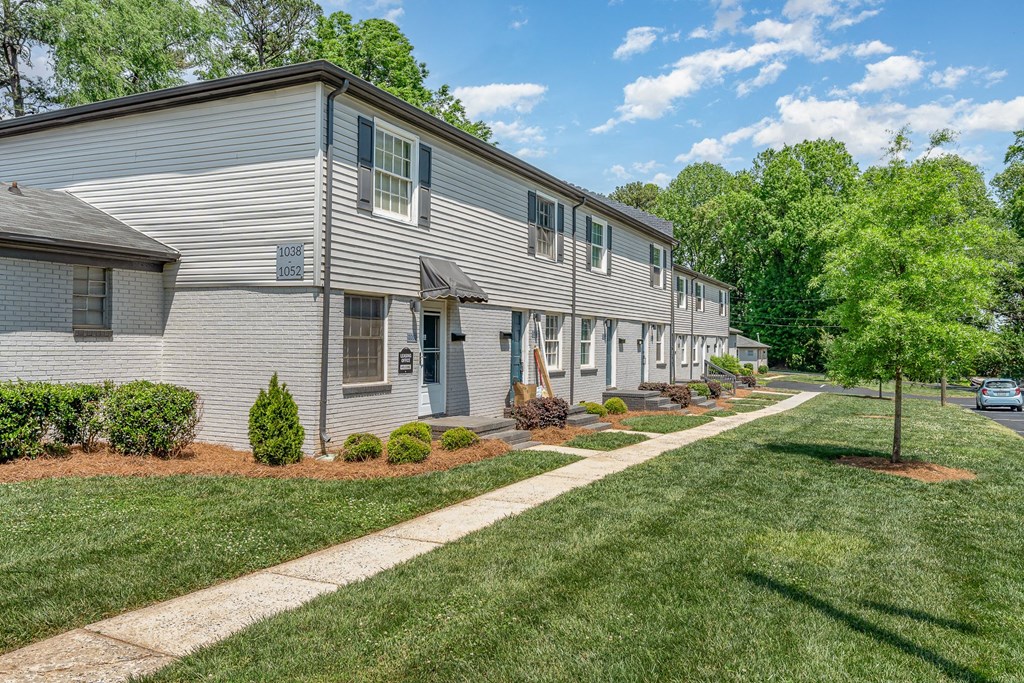 a white house with a sidewalk and grass and trees