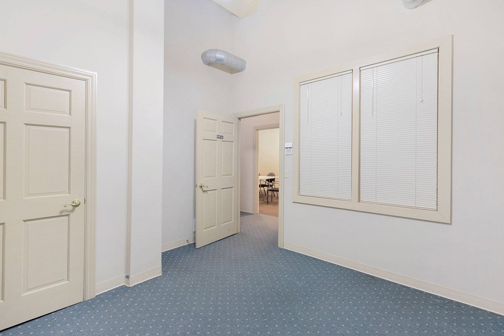A hallway with a blue carpet and white walls.