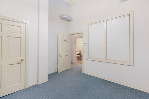 A hallway with a blue carpet and white walls.