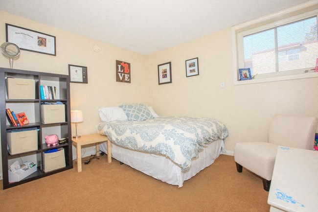 a bedroom with a bed and a chair and a window