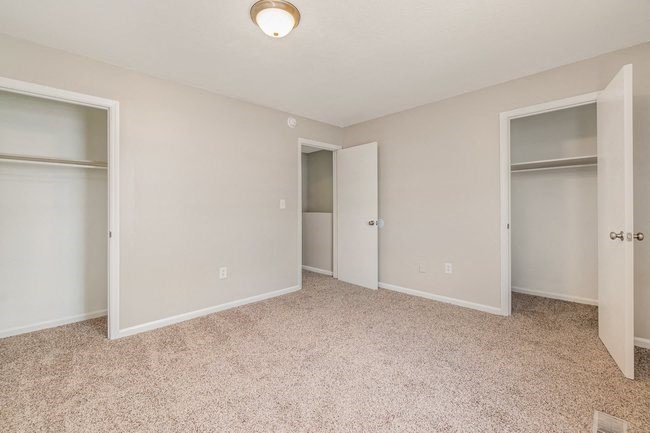 an empty bedroom with two closets and a carpeted floor