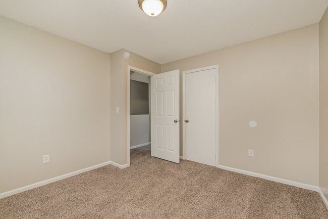 an empty bedroom with a door to a closet