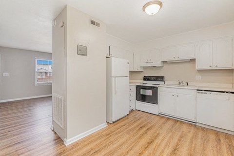 an empty kitchen with white appliances and a wood floor