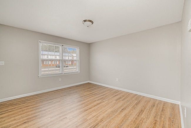 an empty living room with a wood floor and a window