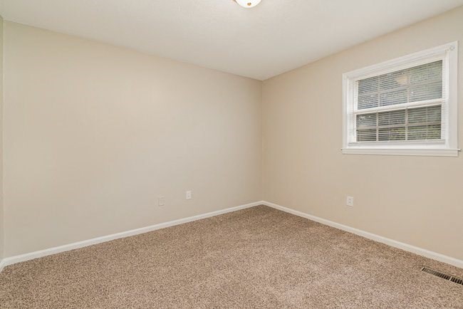 an empty room with a window and carpet