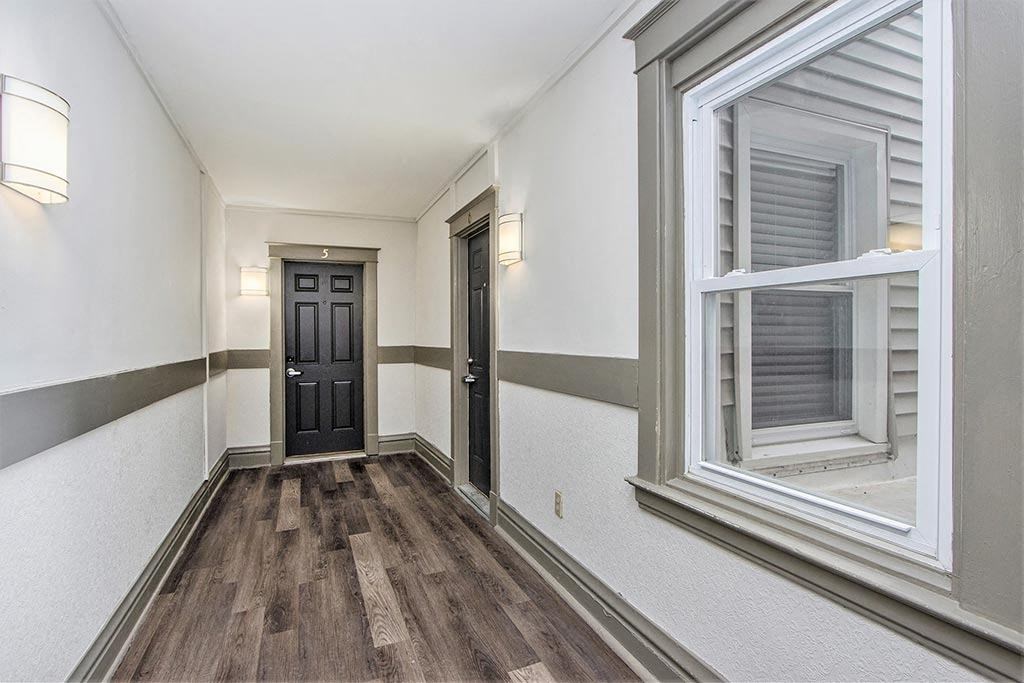 the hallway of a house with a window and a black door