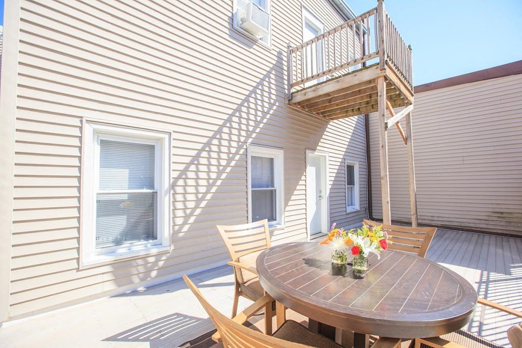 a patio with a table and chairs in front of a house
