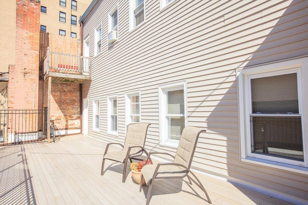 the porch of a home with two chairs on it