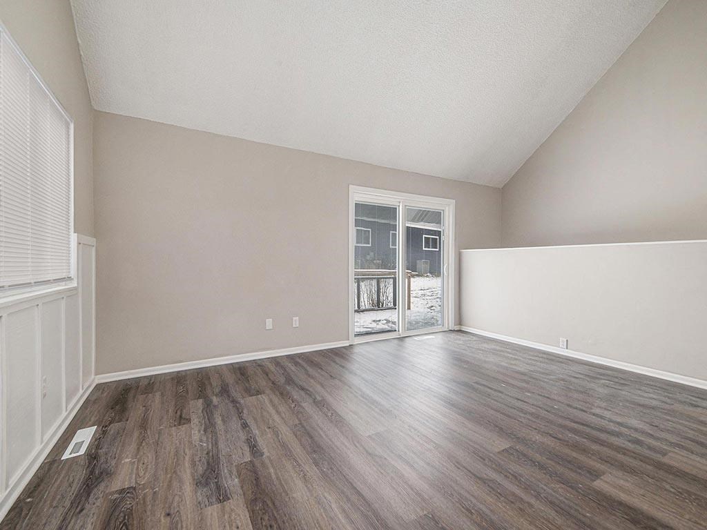 an empty living room with wood flooring and a door to a balcony