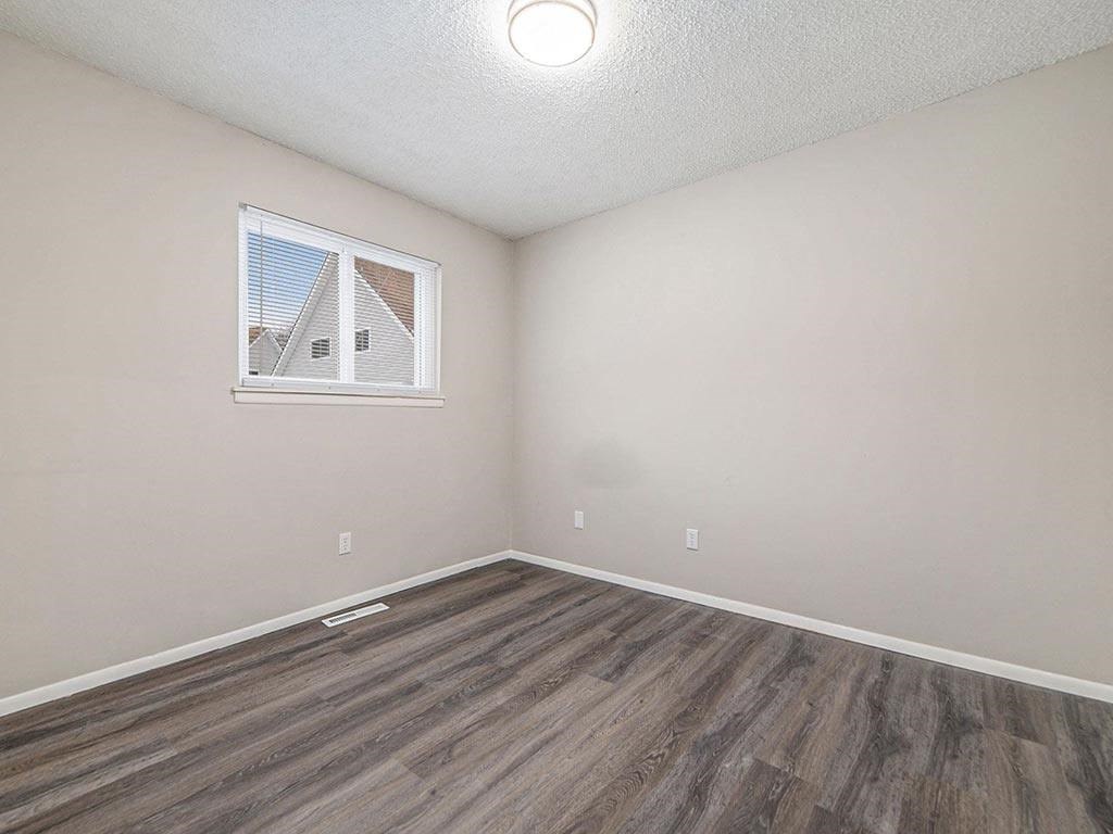 an empty living room with wood flooring and a window