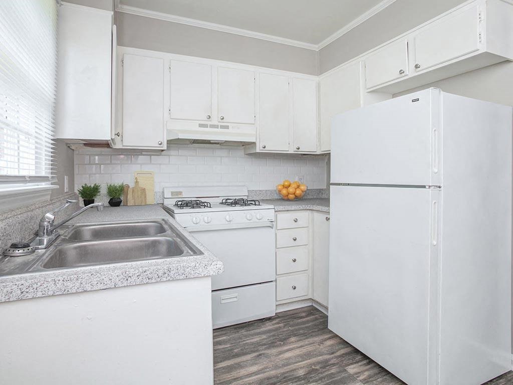 a white kitchen with a sink and a refrigerator