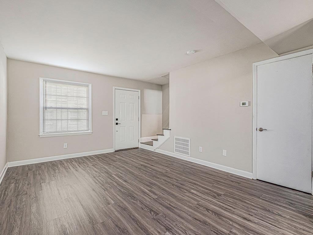 an empty living room with a door to a staircase