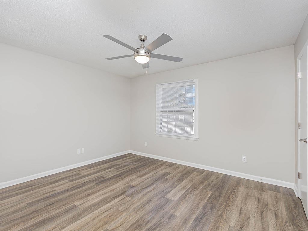 an empty living room with a ceiling fan and a window