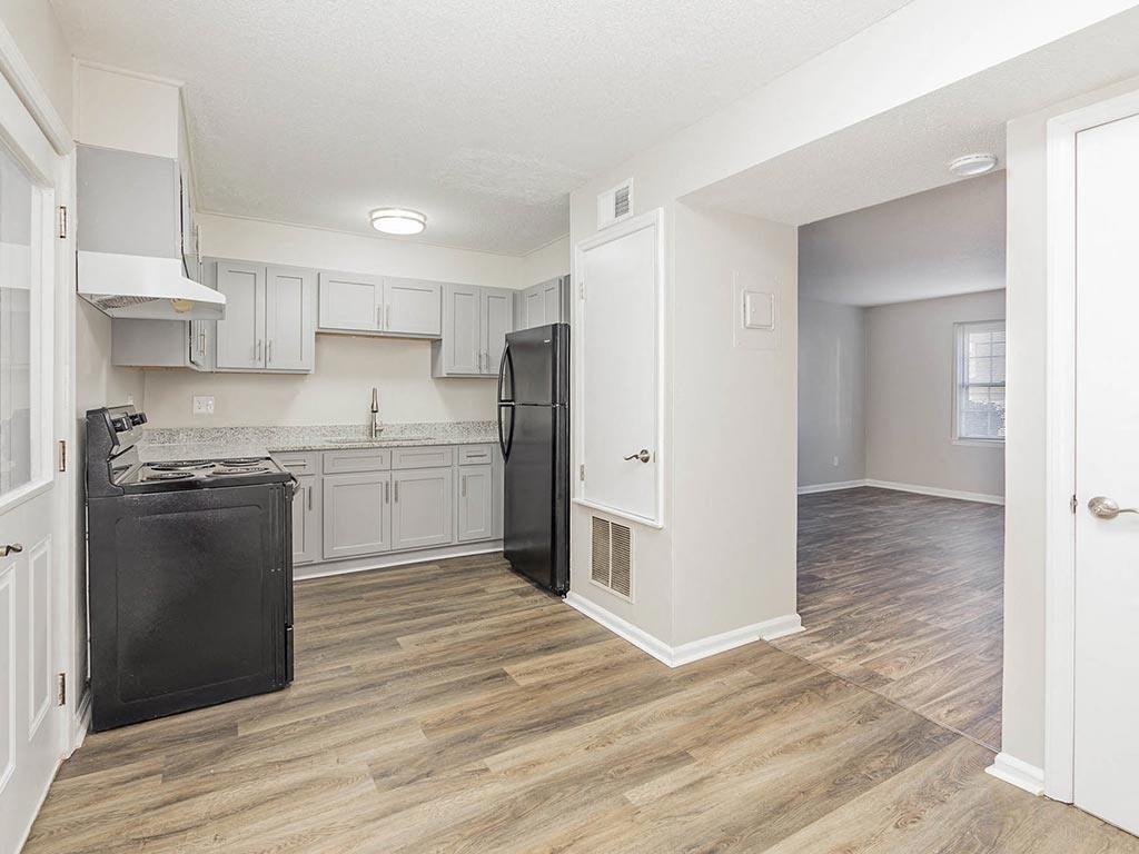 an empty kitchen with a black refrigerator