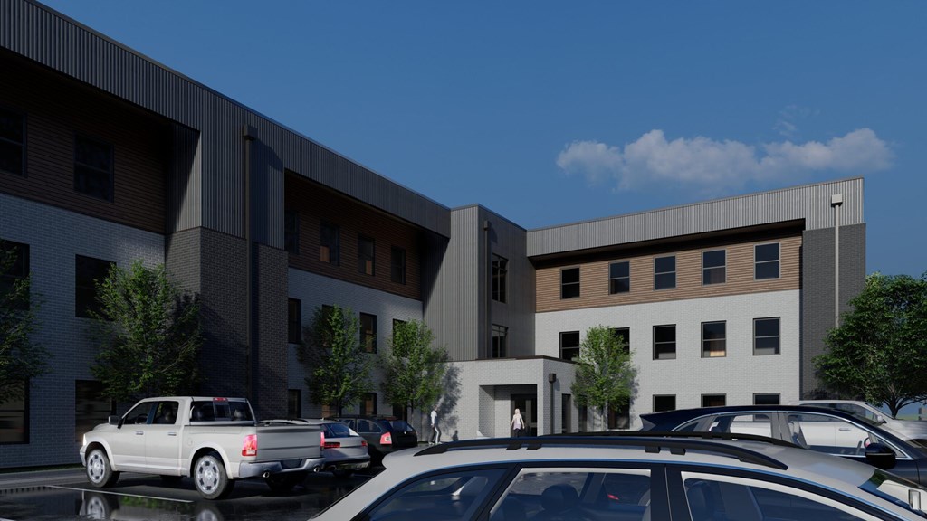 A modern building with a parking lot in front.