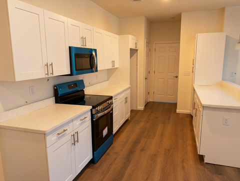 A kitchen with white cabinets and a blue microwave.