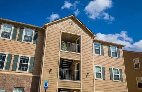 A multi-story apartment building with a blue parking sign in front.