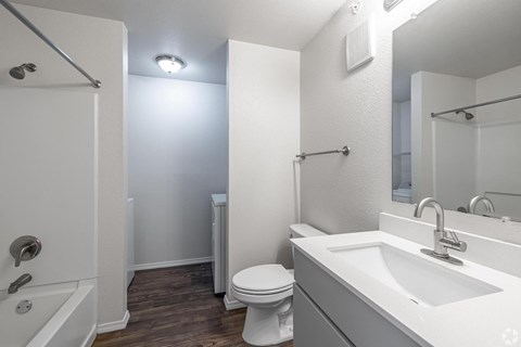 A white bathroom with a toilet, sink, and shower.