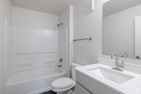 A white bathroom with a toilet, sink, and bathtub.