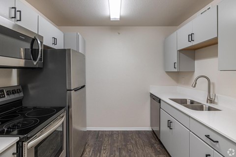 A kitchen with a stove, refrigerator, and cabinets.