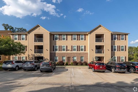 A sunny day at a large apartment complex with cars parked in the lot.