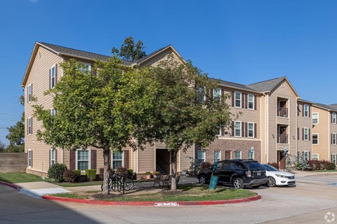 A large apartment complex with a parking lot in front.