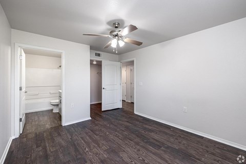 A room with a ceiling fan and wooden flooring.