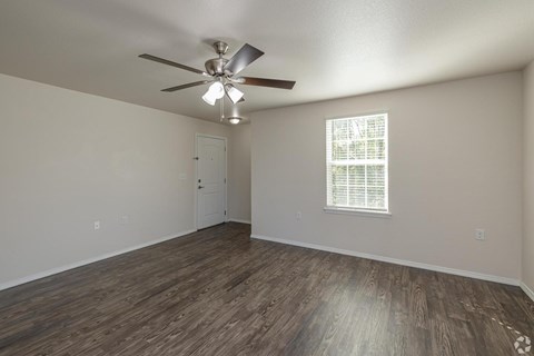 A room with a ceiling fan and a window with blinds.