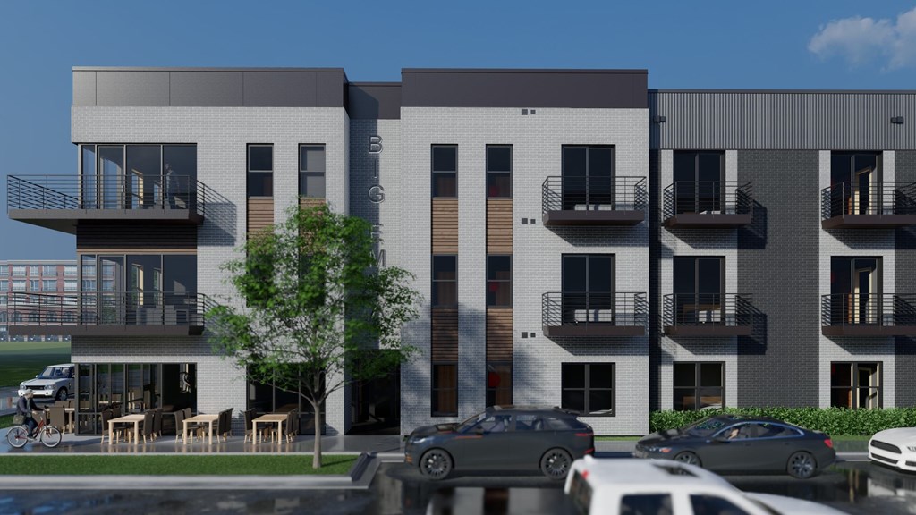 A modern apartment complex with cars parked in front.