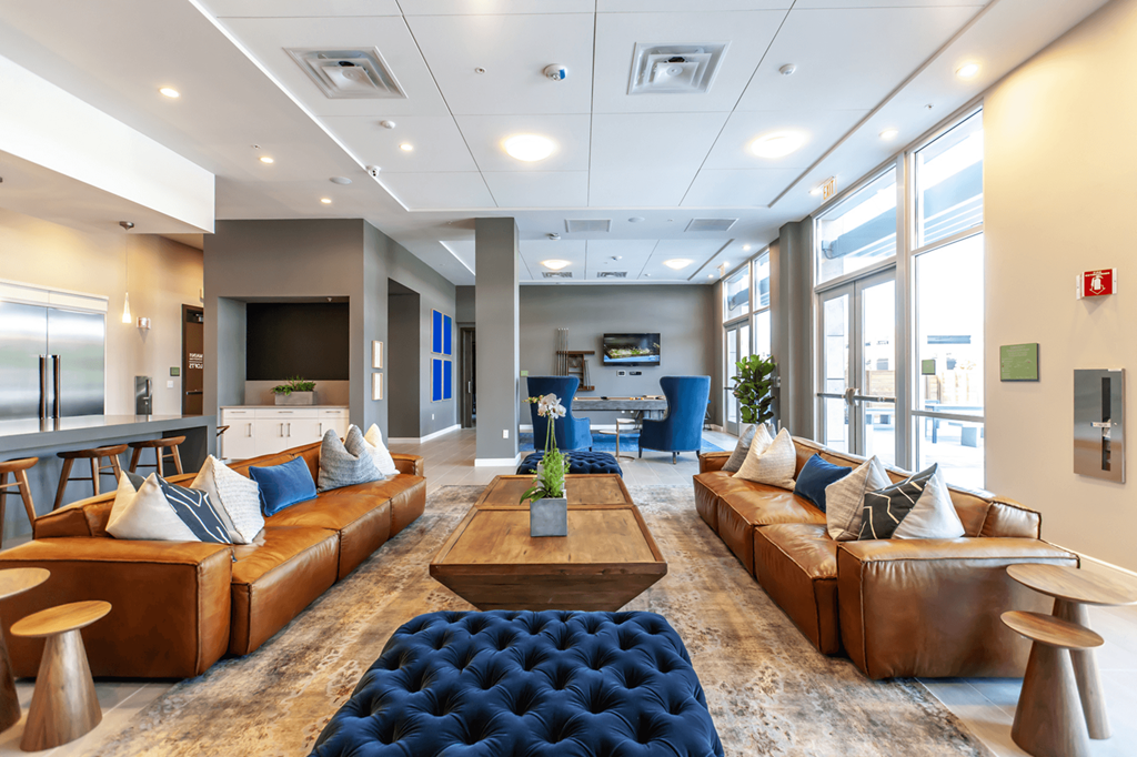 room with leather couches, wooden tables, and large windows inside common area of Main St Lofts Cupertino