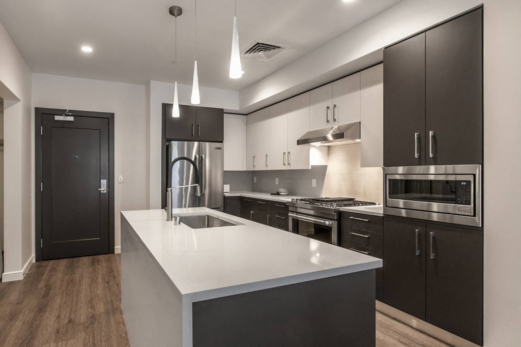 a kitchen with white countertops and black cabinets at Main Street Lofts Cupertino
