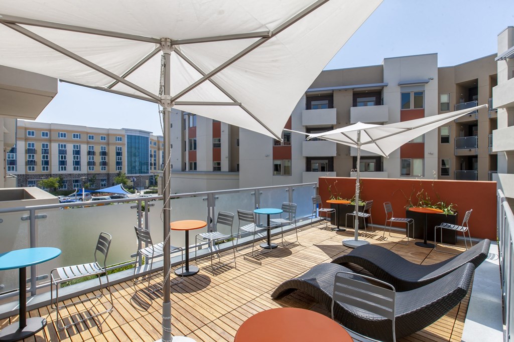 a view of the rooftop terrace of the building with umbrellas and tables and chairs atop Main Street Lofts Cupertino