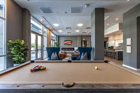 A pool table with a yellow ball and a set of racked balls in the foreground.