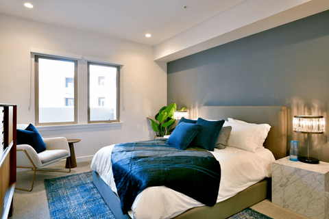 A bedroom with a large bed and a chair by the window.