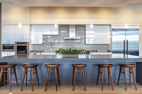 A kitchen with a bar area featuring four stools.