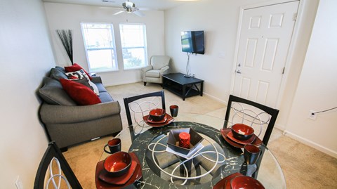 A living room with a grey sofa, a glass table with red bowls and a black bicycle.