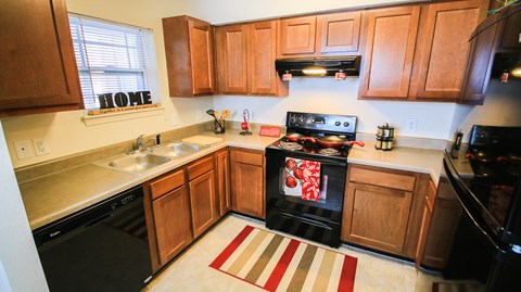 A kitchen with a black stove top oven and wooden cabinets.