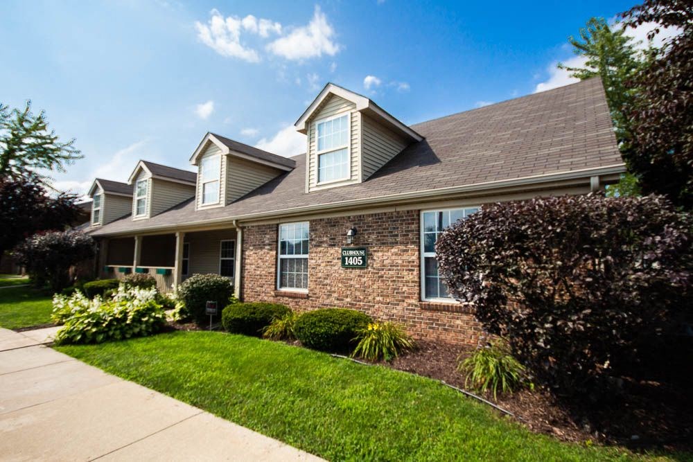 Clubhouse with a green lawn and bushes at Maple Tree Apartments in LaPorte, IN