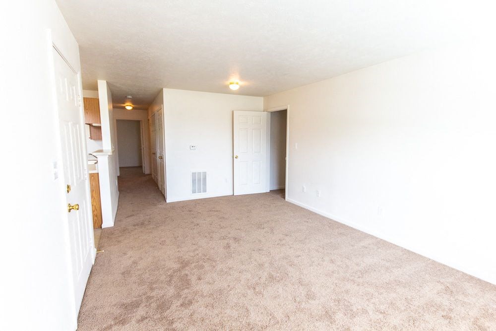 An empty living room with a kitchen in the background at Maple Tree Apartments in LaPorte, IN