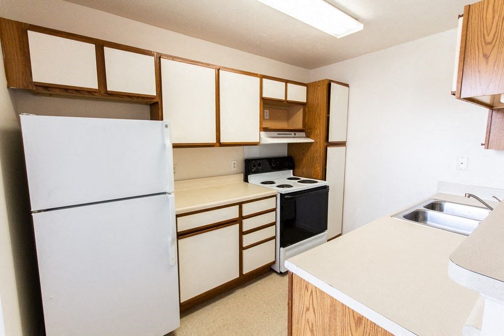Kitchen with white cabinets and a black stove top oven at Maple Tree Apartments in LaPorte, IN