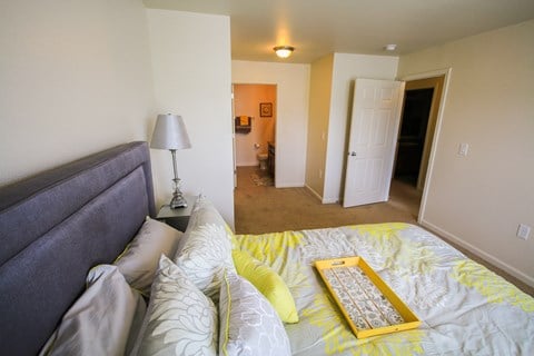 A bedroom with a bed, lamp, and a painting on the wall.