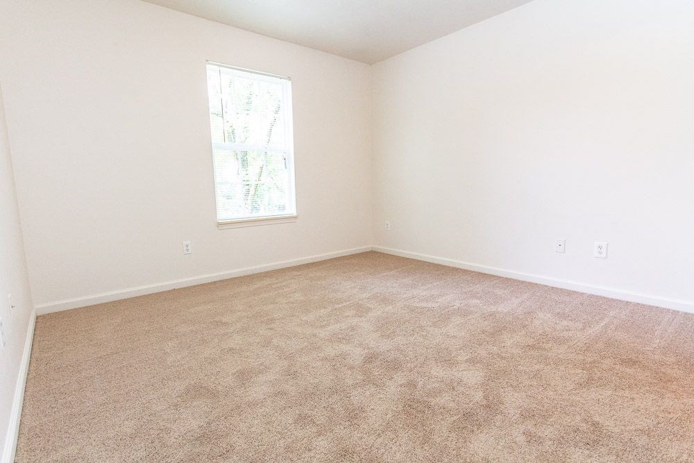 An empty bedroom with white walls, a window, and carpet at Maple Tree Apartments in LaPorte, IN
