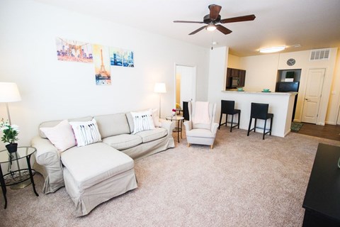 A living room with a white couch and a fan.