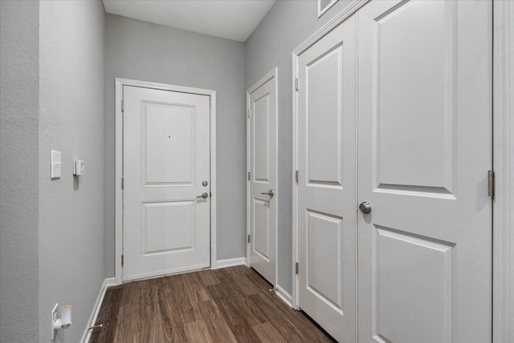 an empty room with white doors and wood floors