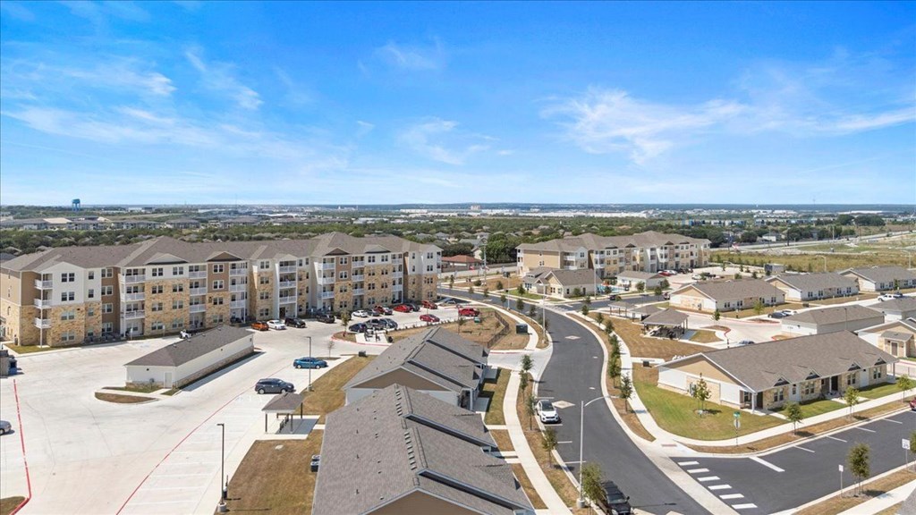 A view of a residential area with apartment buildings and cars parked in the parking lot.