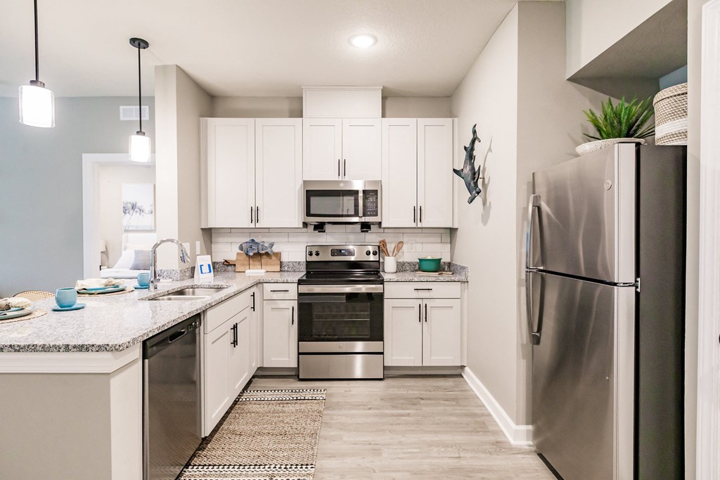 an open kitchen with stainless steel appliances and white cabinets