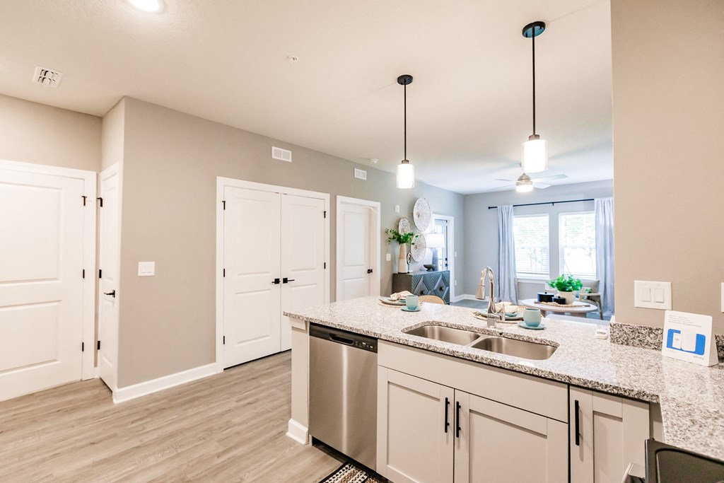 an open kitchen and living room with white cabinets and a counter top