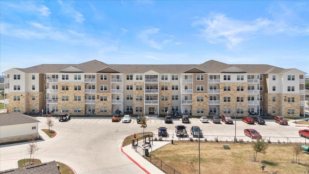A large apartment complex with a parking lot in front.