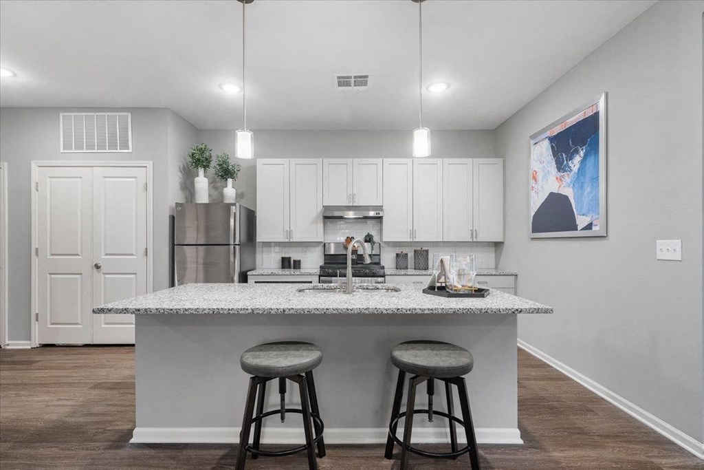 an island with two stools in front of a kitchen